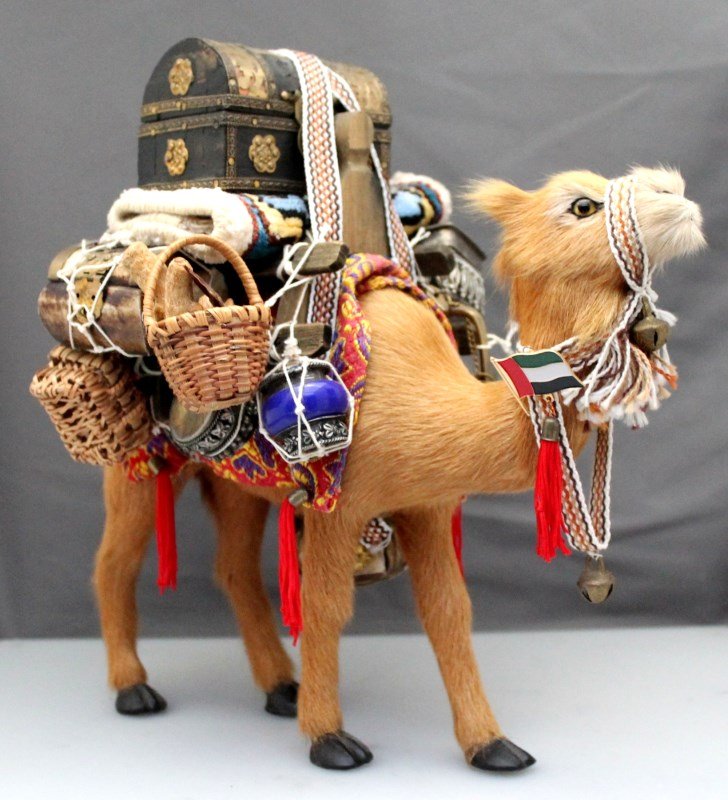 FUR CAMEL FIGURINE DUBAI: A Fur Camel Figurine purchased in Dubai. Laden with persian rugs, brass lamps ornate trunks and bone and silverwork boxes, gold ottoman and more. PROVENANCE: A Hilton Head South Carolina Private Colle