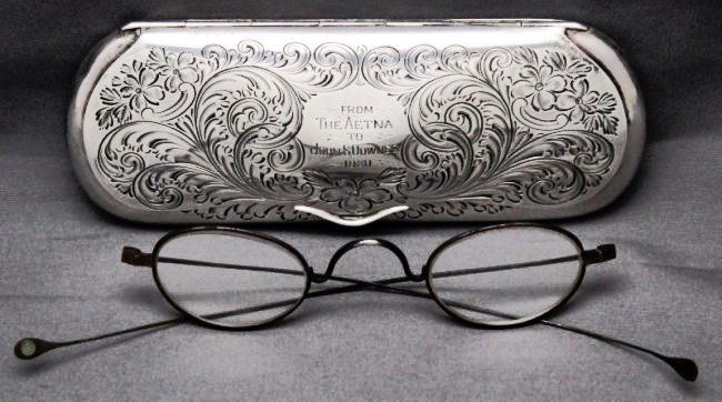 STERLING SILVER EYEGLASS CASE 1920: Ornate Solid Sterling Silver Eyeglass Case. With finely engraved floral and plume, 70 grams. Engraved From The Aetna to John S. Downes 1920. A pair of antique wire frame spectacles included. Measures