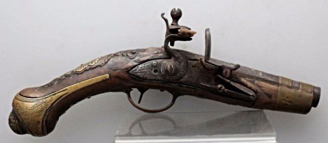 19th C. OTTOMAN FLINTLOCK PISTOL: Antique 19th century Flintlock Pistol, made for the Turkish Market. Makers name on side. Wooden stock with inlaid bronze, ornate chase work, ornamental butt cap. Touh marks on barrel band. The wood ha
