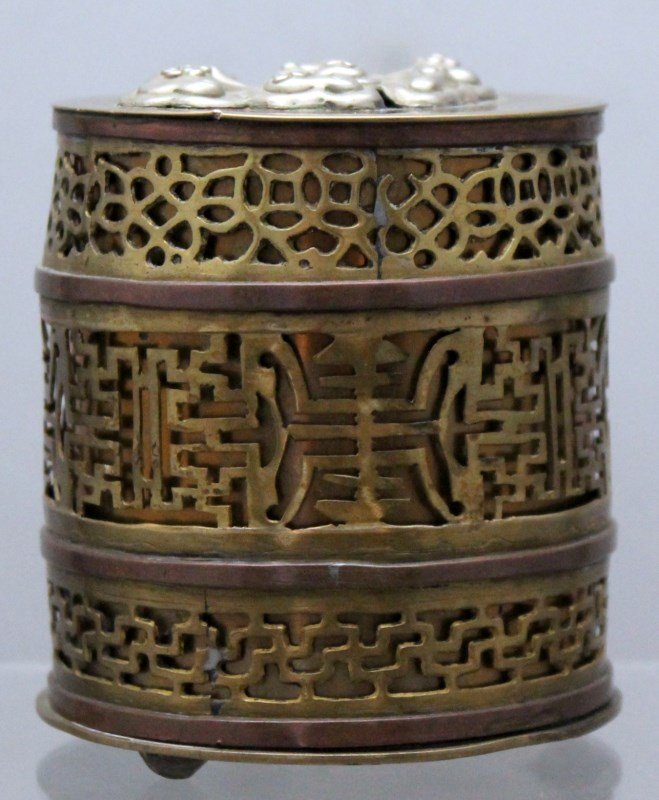 ANTIQUE BRASS OPIUM BOX: Antique Brass Opium Box.The box lid with pierced sides copper bands, top with silver and 3 silver ball feet 2.75 round, 3 1/8" tall. 7.5 oz. PROVENANCE: A Charleston SC Private Estate