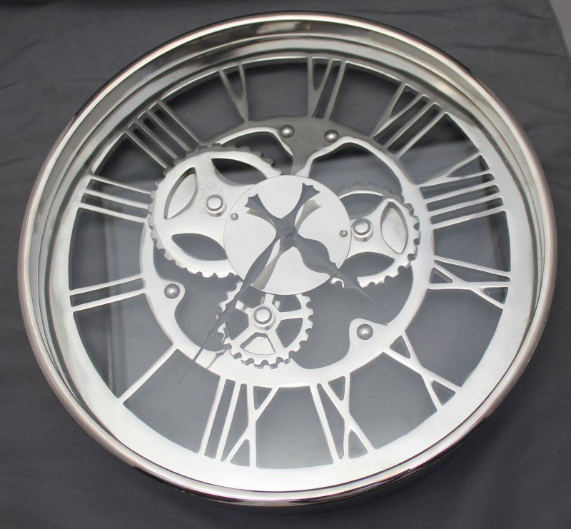 ZODAX REGATTA POLISHED NICKEL WALL CLOCK: Decorator Zodax Regatta Modern Polished Nickel Wall Clock. The Regatta features a cut-out face with exposed gear design and large Roman numerals. The Regatta collection of by Zodax embodies casual sop