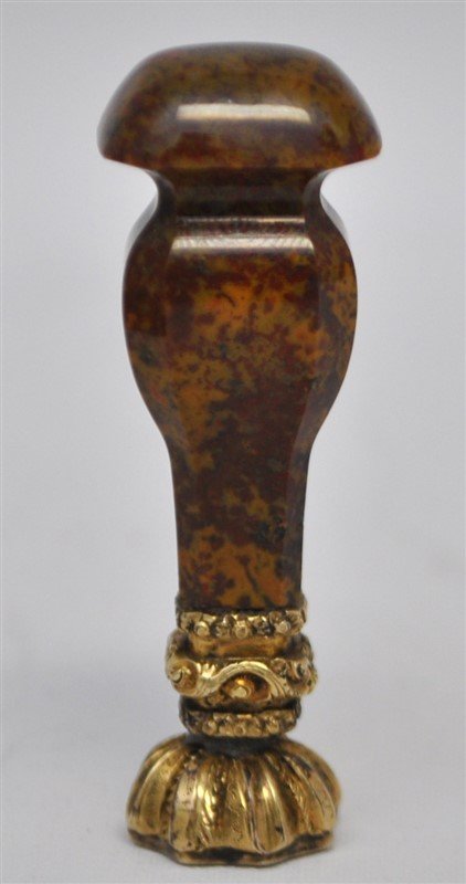 GEORGE III CARNELIAN PUDDING STONE DESK SEAL: A late George III / early Victorian Carnelian Pudding Stone desk seal. The gilded mounts unmarked, the waisted rectangular section handle with chamfered edges. Measures 2.25" tall. Weight is 1.1 oz. P