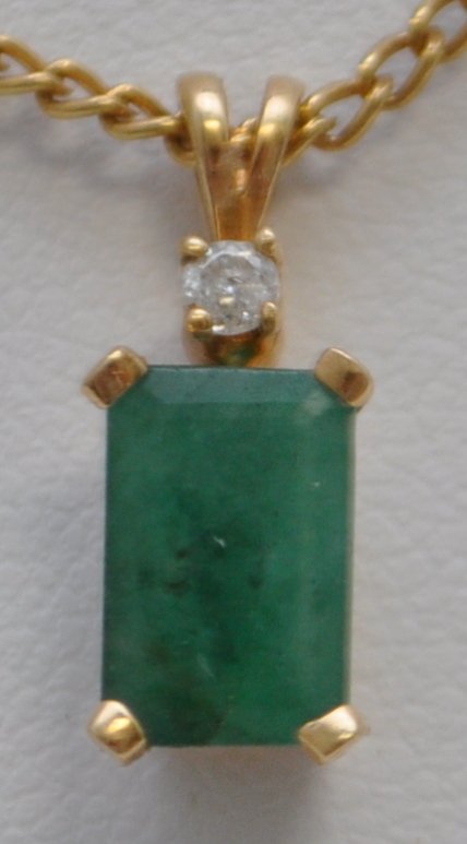14KT 1.40 CT EMERALD & DIAMOND PENDANT: One lady's 14kt yellow gold emerald & diamond pendant on an 18" gold plated chain.The pendant measures approx. 16.80mm tall and features one (1), four prong set, emerald cut emerald set in a basket st