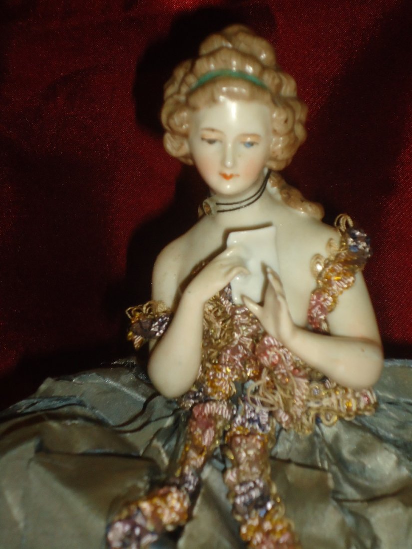 German Porcelain Half-Doll Pin Cushion: Outstanding German porcelain half doll, beautifully detailed sewn into an ornate "dress" pincushion. Slight damage to two finger tips. 8" tall.