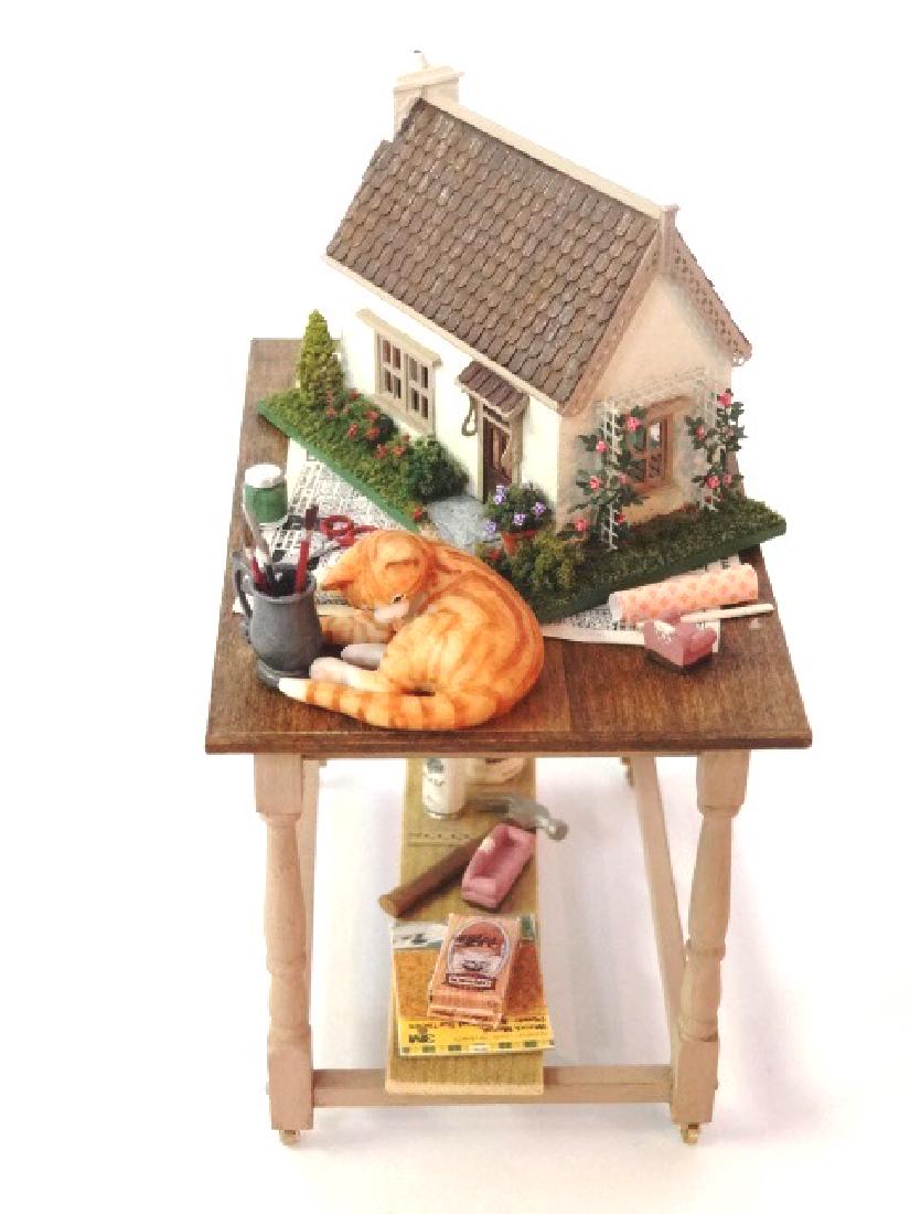 Nell Corkin Miniature Dollhouse Diorama: Nell Corkin miniature two room cottage diorama set on a table with crafting supplies and a sleeping cat, made for the 1994 IGMA auction, 3.75"W, 4.75"H, 2.5"D