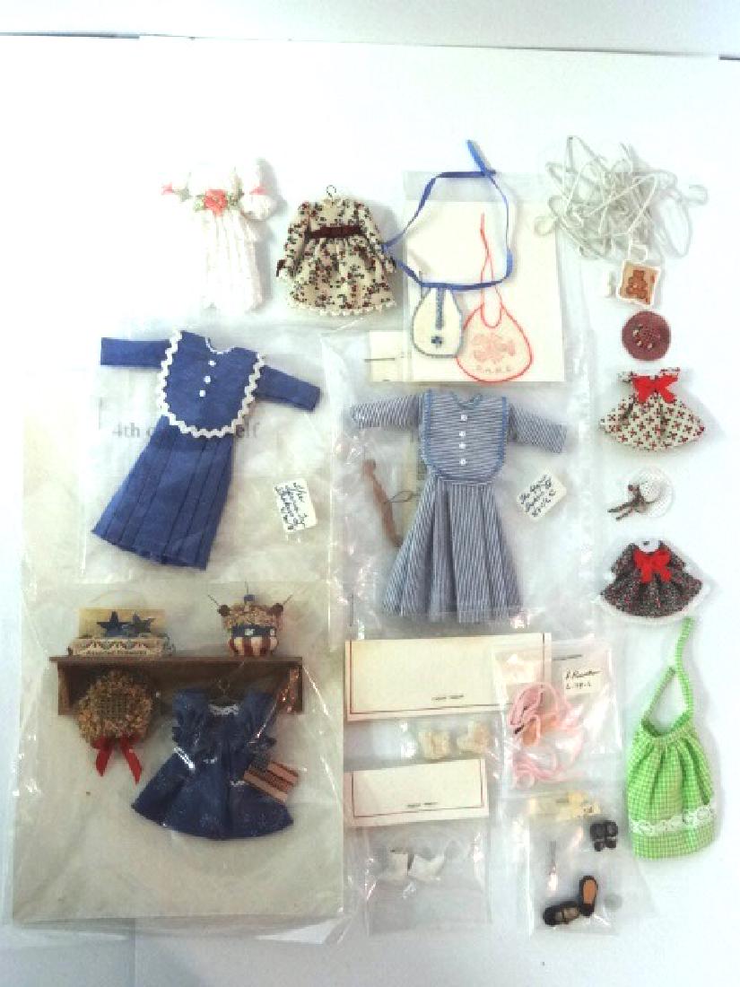 Dollhouse Artisan Children's Clothing Miniatures: Fourth of July dress with straw bonnet, flag, box of fireworks and basket of firecrackers all on a mahogany shelf 3.5"W, two Quaker dresses by The Shaker Tree, bibs, shoes, dresses, apron, hangers, te
