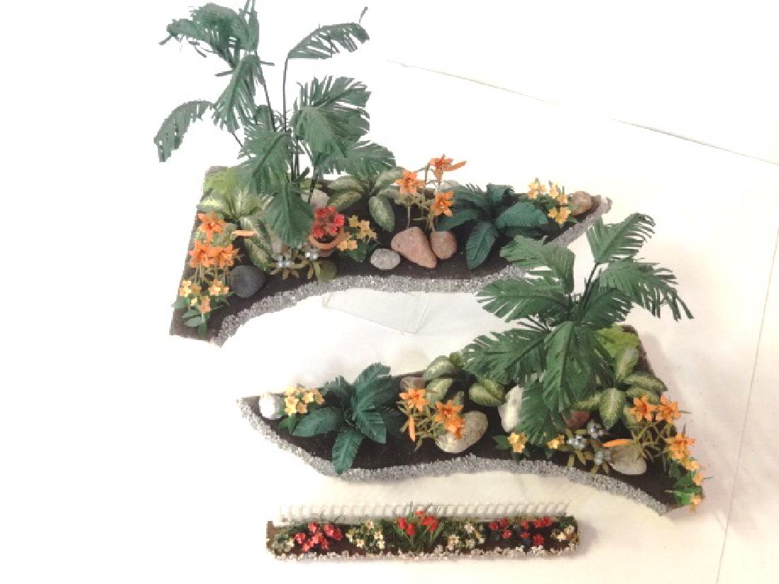 Two Maggie Bock Dollhouse Flower Beds Miniatures: Two artisan dollhouse flower beds attributed to Maggie Bock filled with ferns, flowers and rocks 9" by 4.5", also a flower bed with fence by unknown artist 6"L