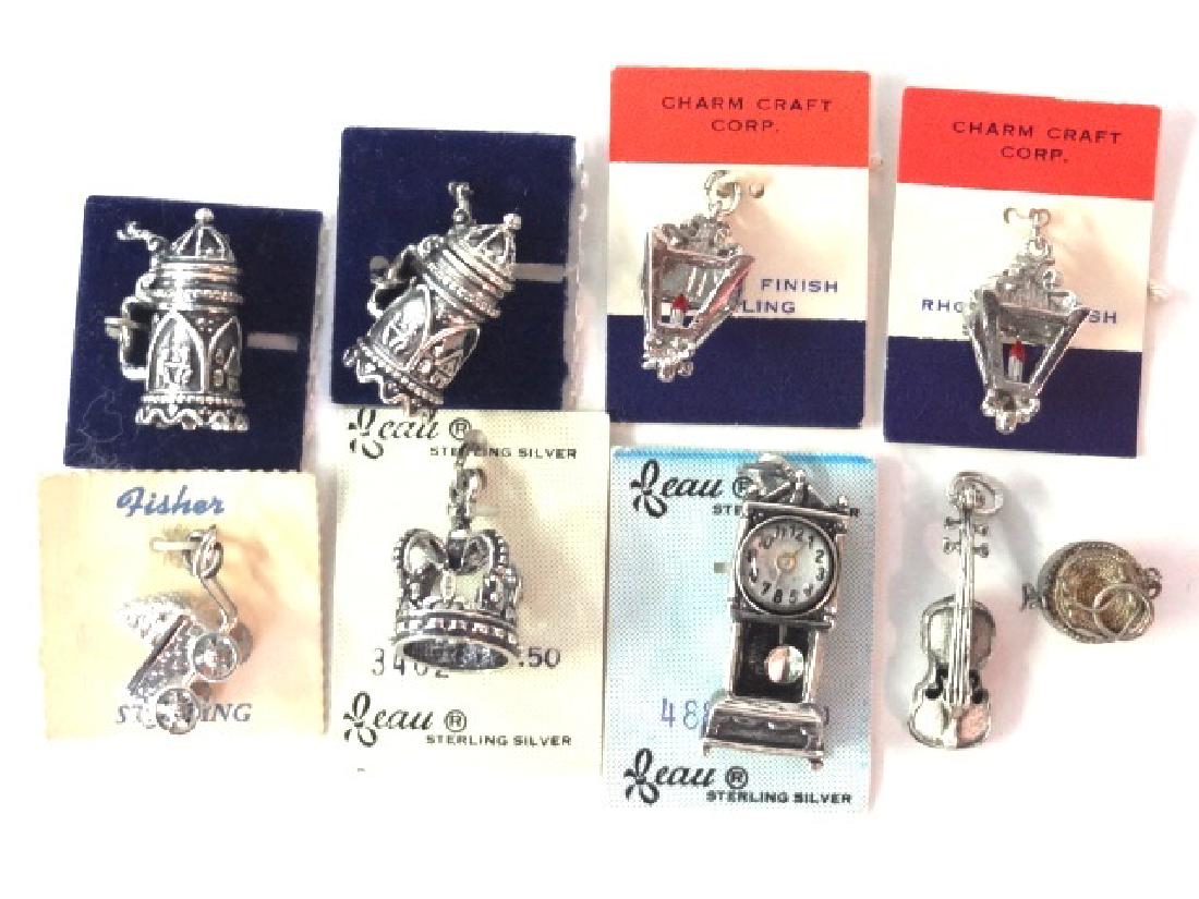 Miniature Sterling Charms: Four Beau sterling charms, grandfather clock 1 1/8"H, crown and two tankards, Charm Craft pair of lanterns, Fisher baby carriage, violin marked sterling 1"H, also unmarked silver colored basket charm