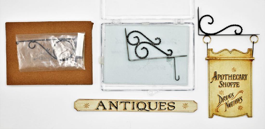 Schlosser Dollhouse Signs & Brackets Miniatures: George Schlosser hand painted double sided Apothecary Shoppe wood sign with metal hanging bracket 4.5"H by 2.5"W overall in original envelope, hand painted single sided Antiques sign 5"L, metal sign b