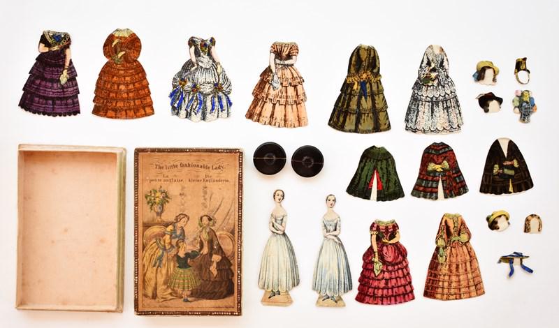 The Little Fashionable Lady Paper Doll Set: Mid-19th century boxed paper doll set The Little Fashionable Lady, hand colored two part box printed in English, French and German, includes two 4.5" front and back dolls with two wood stands, 8 front