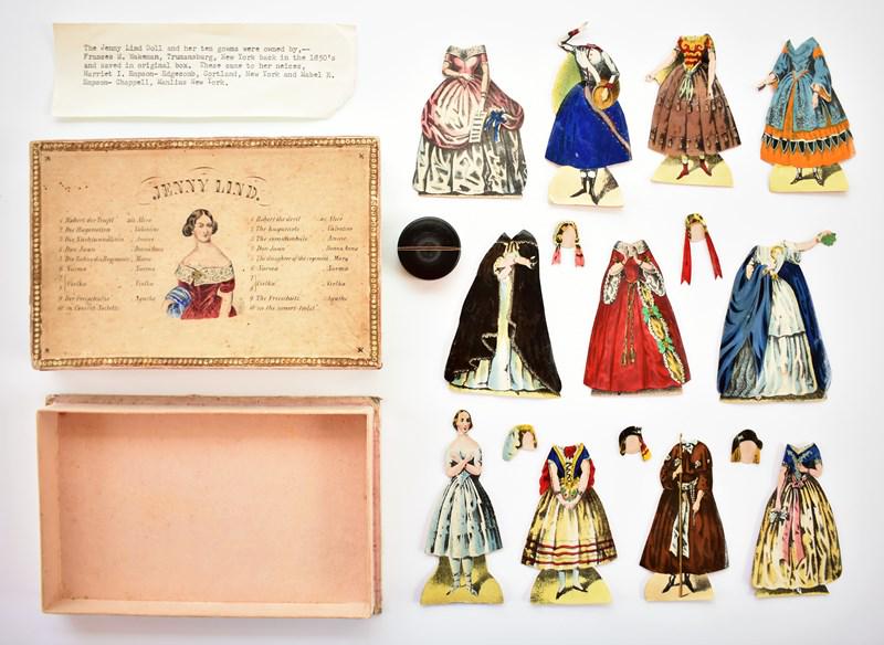 Jenny Lind Boxed Paper Doll Set: Dating to the mid-19 century is a boxed Jenny Lind set, two piece hand colored box in very good condition with one flap corner split 4.25" by 6.5", 4" doll with neck bend and 10 costumes and 5 hat or 
