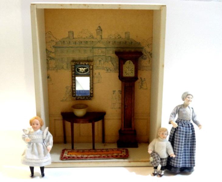 Three Bisque Dolls & Vignette Box Dollhouse Miniatures: B. Hague artisan character doll with millwork dress 5.5"H, pair of children bisque dolls, vintage vignette room with tall case clock, demilune table, needlework runner and a turned stone bowl 8 3/8"W,