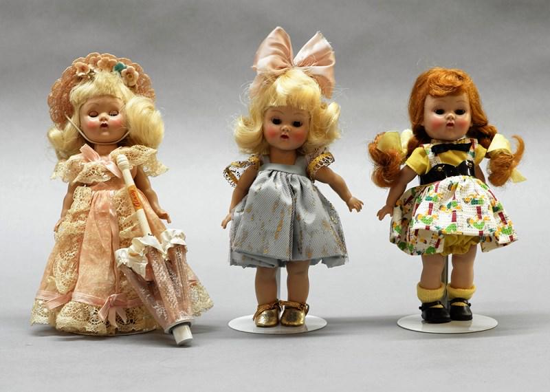 Three Vogue Ginny Dolls: Three 7" hard plastic straight leg walker dolls, pink formal & blue dress are tagged, yellow & white is not tagged, has umbrella w/pink formal