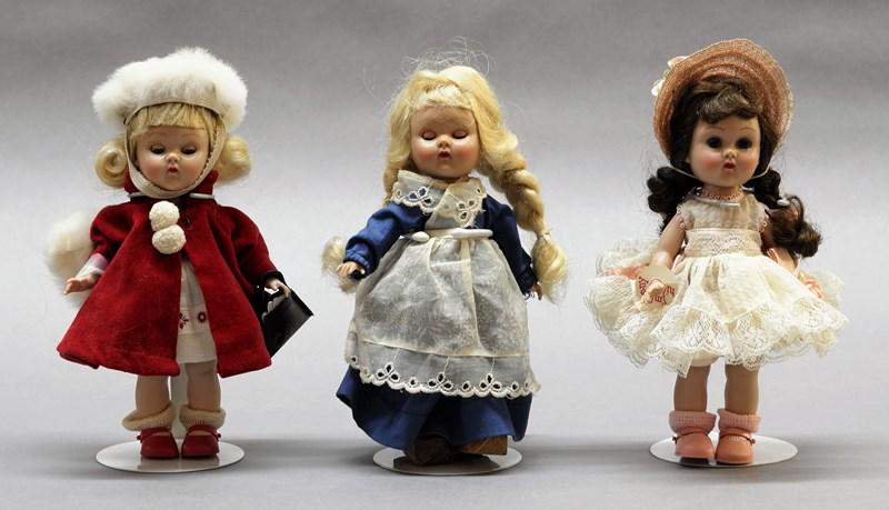 Three Vogue Ginny Dolls: Three 7" hard plastic straight leg walker dolls in original tagged clothes, one has Ginny wrist tag w/zipper closure dress, one has Velveteen coat w/white fur muff & hat along w/Ginny purse & gloves, 