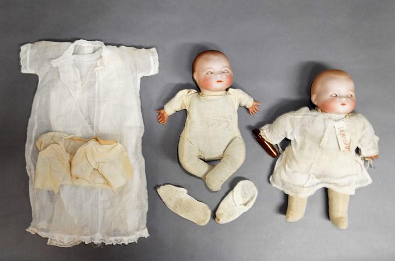 Two Bisque Dolls: AM 12" My Playmate bisque head doll. Head good, original dress w/tag, celluloid hands with bottle. Grace Storey Putman 10" Bye-Lo Baby. Head cracked, body marked Bye-Lo Baby, dress tagged same