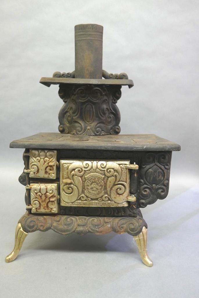 Antique Child: Antique child's Favorite cast iron stove made by the Favorite Stove & Range Co. Pique Ohio, heavily scrolled and embossed six burner stove with warming shelf and flue pipe, three nickel plated doors c