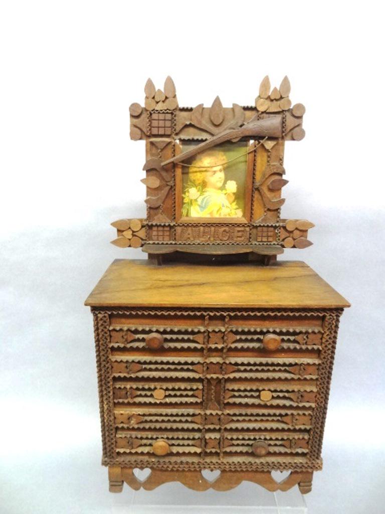 Tramp Art Miniature Dresser: Antique doll sized tramp art dresser, mahogany with recycled cigar boxes for drawers, single drawer over two drawers over a single drawer, scalloped skirt with heart cut-outs, frame has carved rifle a