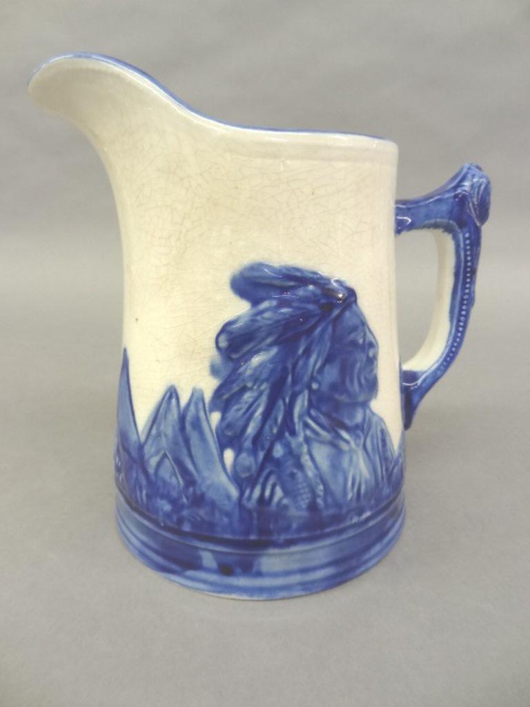 Old Sleepy Eye Ironstone Pitcher: Early 19th century Old Sleepy Eye pitcher with blue and white glaze, embossed design of Indian Chief and encampment, 8"H