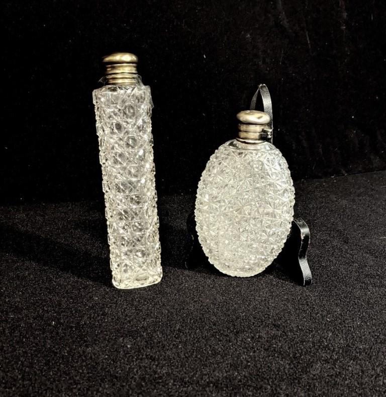 Two Antique Cut Glass Flasks: Antique oval flask with glass stopper and brass hinged lid 7"H, flat oval decanter with monogrammed silver colored hinged lid which is stuck shut 5.5"H