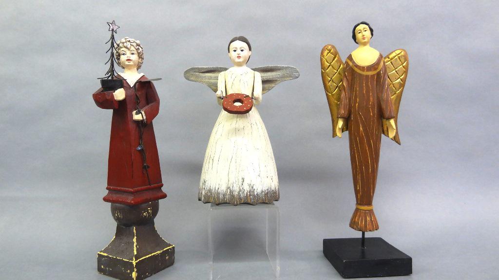 Three Artisan Christmas Figures: Three contemporary artisan figures, carved wood angel on base 14.5"H, carved wood angel holding a wreath 10"H, composition girl holding a metal xmas tree and hoe 14"H