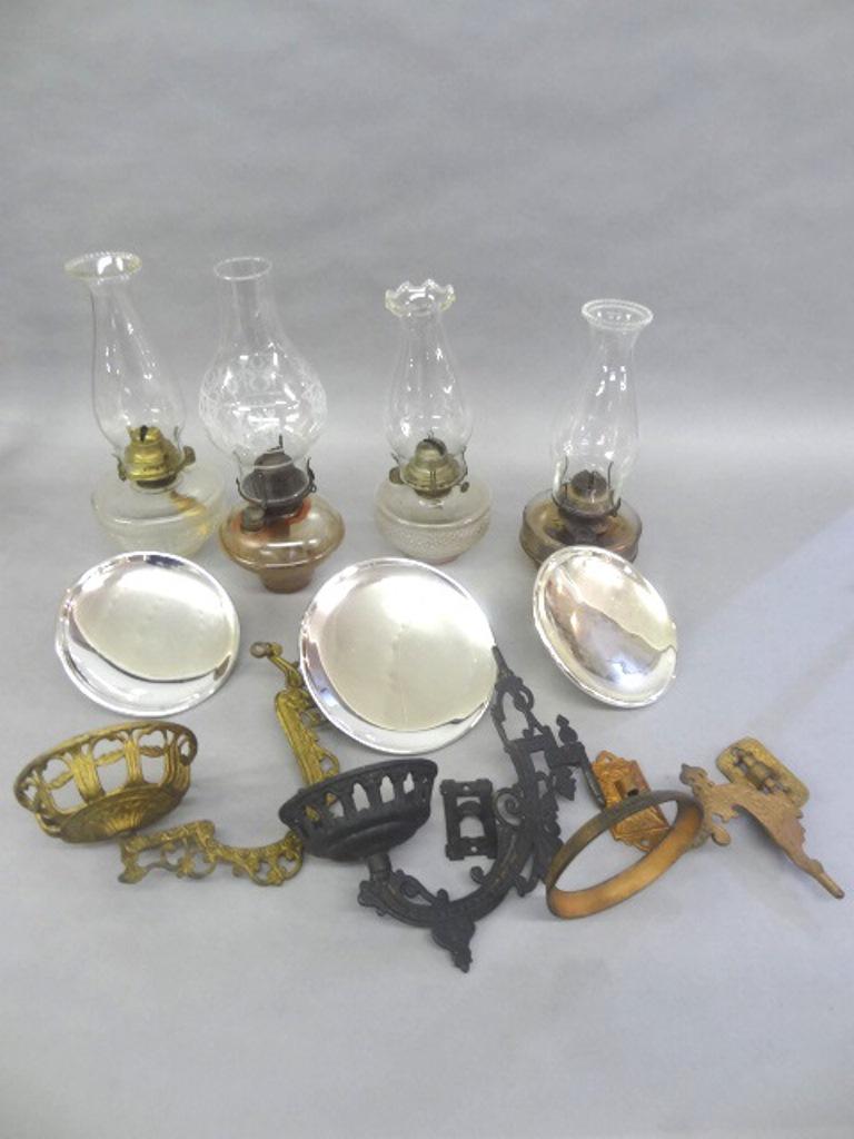 Four Wall Hanging Kerosene Lamps: Group of four assorted glass kerosene lamp with chimneys 12.5" to 14.5"H, includes three hanging brackets with wall mounting plates and four glass reflectors