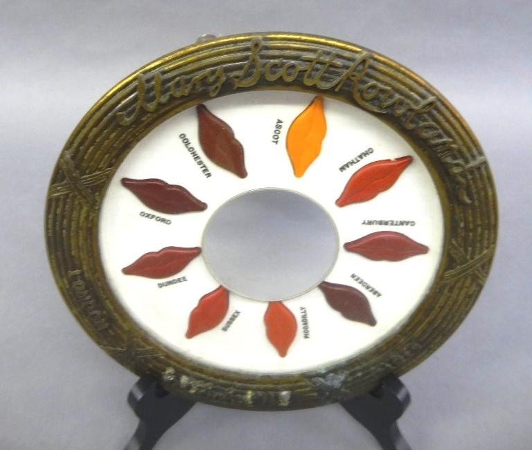 Mary Scott Rowland Lipstick Store Display: Unusual store display, heavy ribbed brass frame signed "Mary Scott Rowland London Paris Established 1881", inset with round mirror surrounded by various colors of lipstick, 10"D