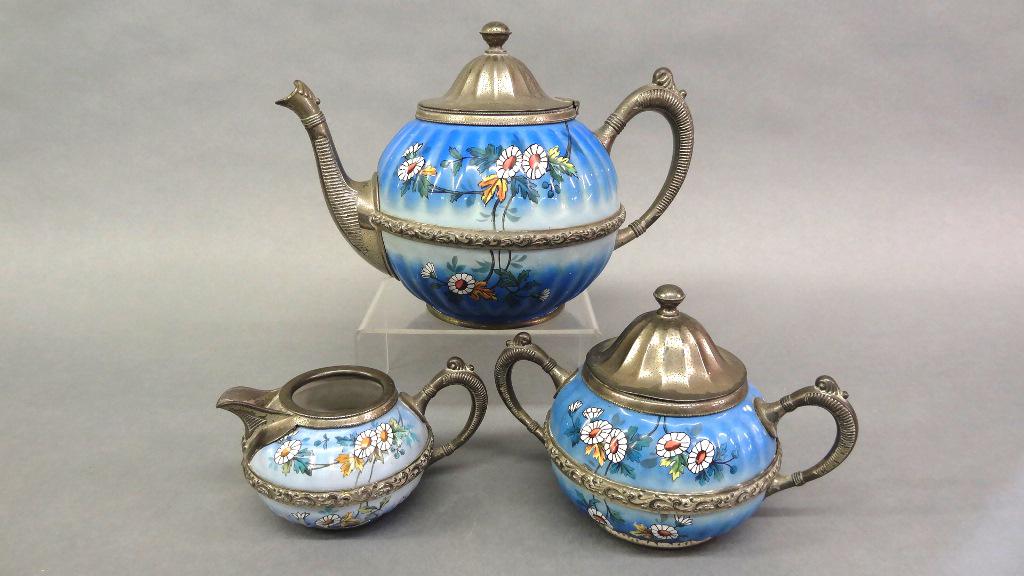 Manning Bowman Enamelware Tea Set: Antique Manning Bowman three piece tea set, enamelware with daisy floral decoration and silver-plate mounts, teapot 10.5"L, sugar bowl 8"W, creamer 5.5"L
