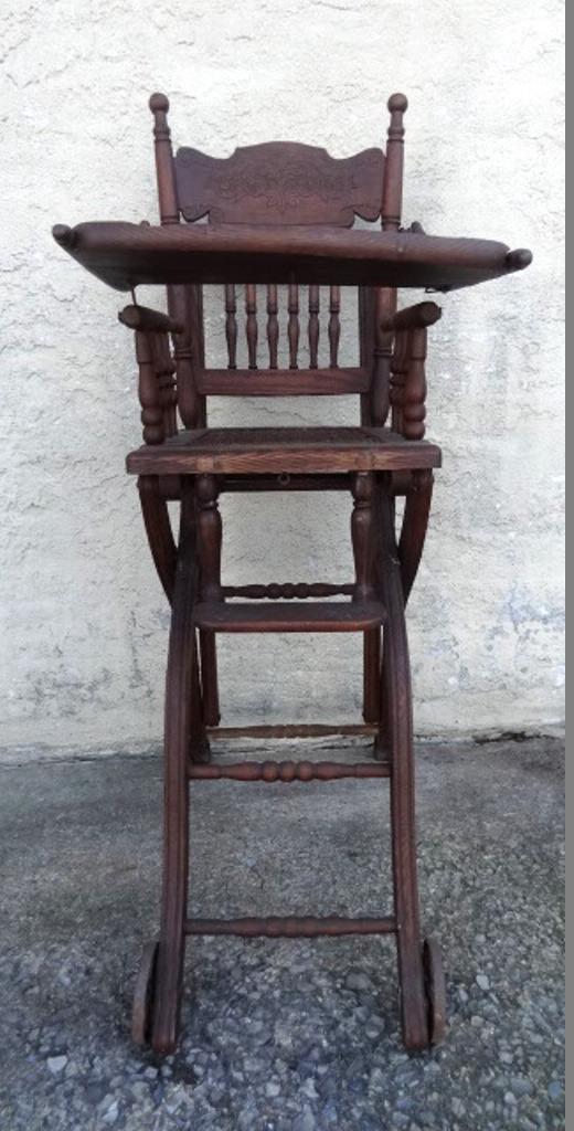 Antique Oak Pressed Back High Chair: Antique child's high chair with pressed back, spindle turnings, woven seat, hinged tray and iron wheels, 41"H, 17"W, 5"D