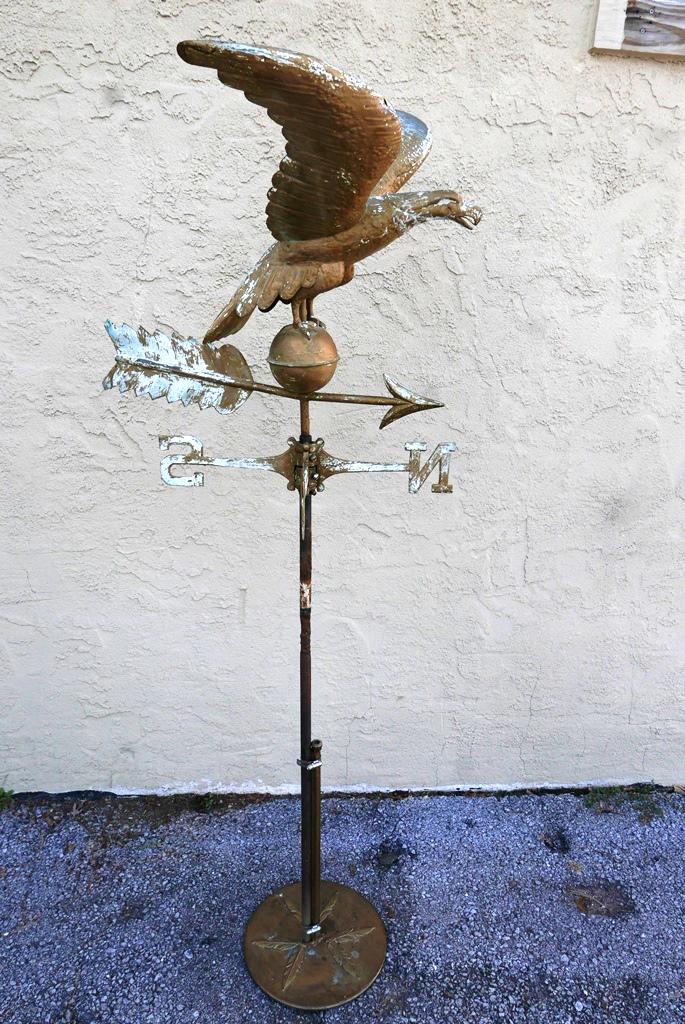 Vintage Eagle Weathervane On Stand: Vintage hollow body spread wing eagle weather vane with directional arrow 23"L, 18"H, 21"W, retaining weathered old paint, includes home made stand with NSEW directionals, 61"H overall