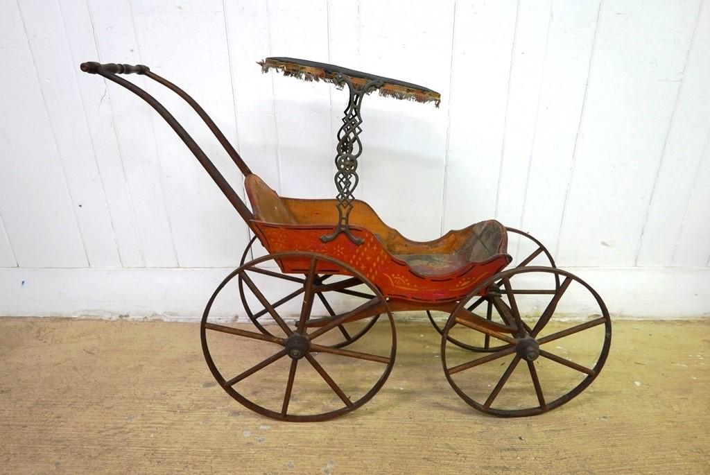 Antique Painted Doll Stroller: Antique late 1800's child's doll stroller, red painted body with stenciling and pinstripes, padded sharkskin top with fringe and adjustable iron brackets, original blue seat covering, painted woven gr
