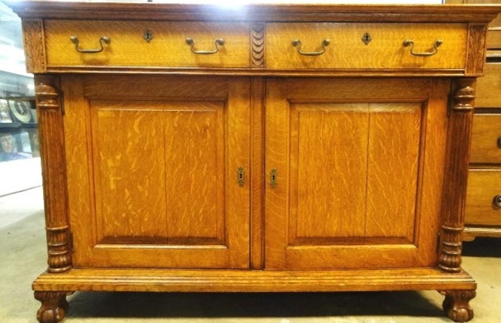 19th Century Oak Sideboard: Late 1800's oak sideboard with beautiful quarter sawn figure, two board top, paneled sides, two half width drawers with original brass pulls, locks and escutcheons flanked by carved acanthus leaf pane