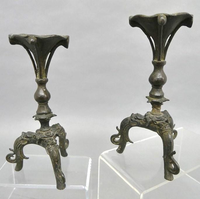 Pair of Archaic Bronzed Pricket Candlesticks: Pair of heavy archaic style pricket candlesticks, brass with dark applied patina, flower form top on a tripod base with stylized elephant head legs 10.25"H