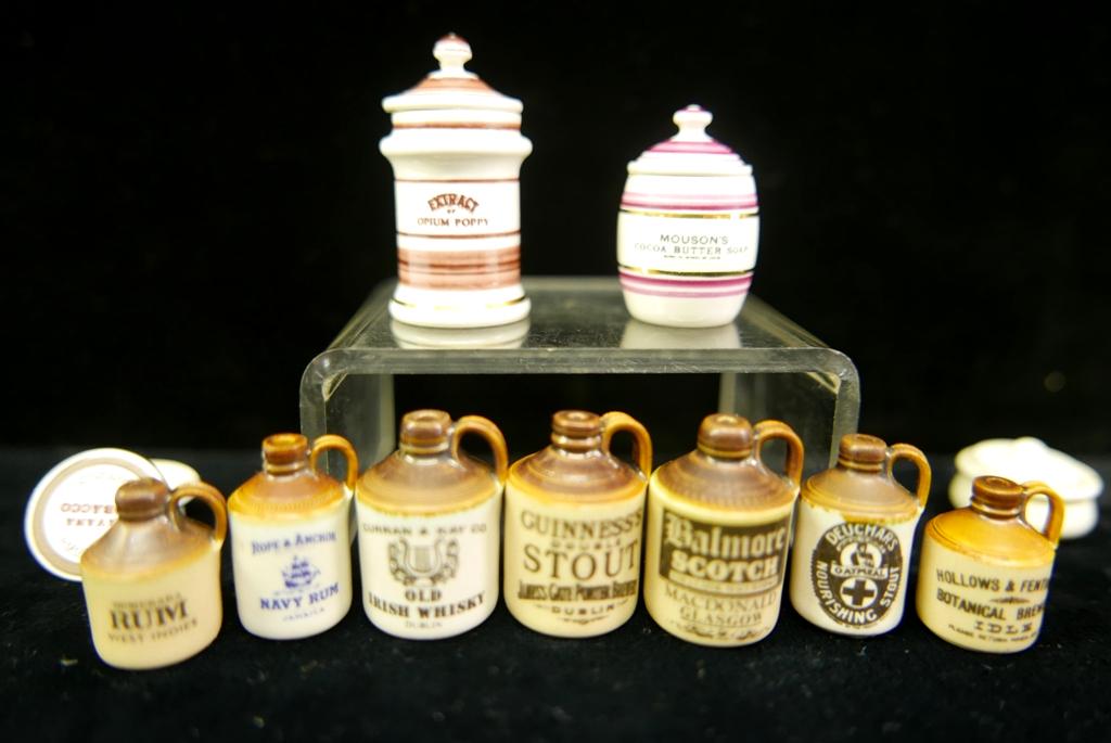 Terry Curran Dollhouse Artisan Ceramics: Nice group of signed Terry Curran accessories, seven advertising jug with the tallest 1", advertising tobacco jar, butter soap canister, opium poppy canister 1.5"H, also includes a Carolyn Curran cove