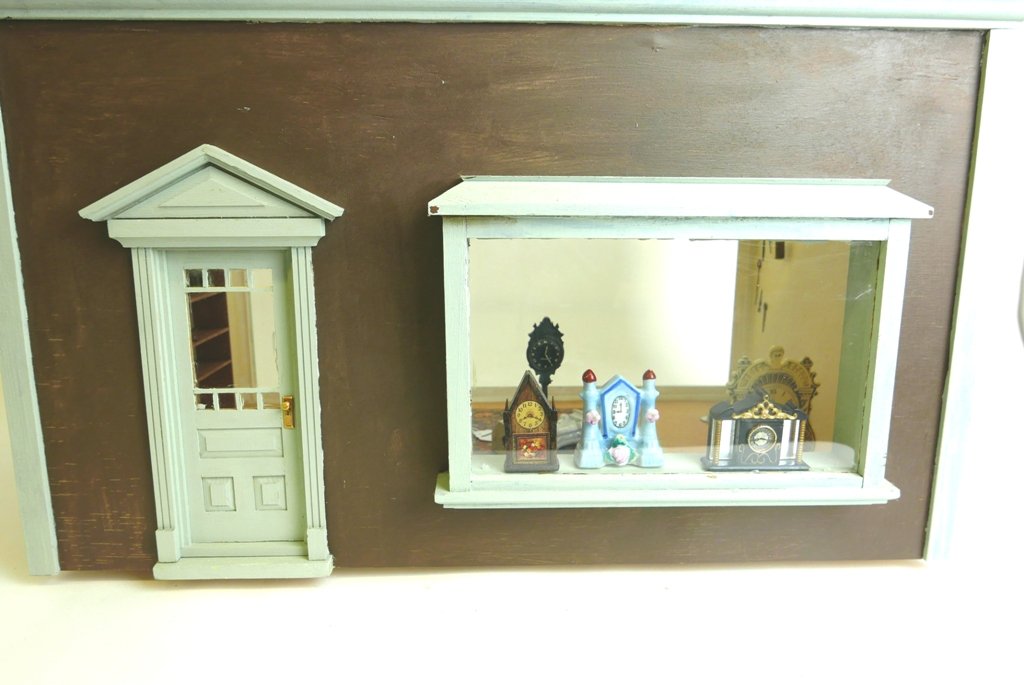 Furnished Clock Shop Dollhouse Room Box: Painted wood room box clock shop has one piece Plexiglas cover for top and front access, rear has large bay window and stationary door, interior has painted walls and papered floor with a nice quality