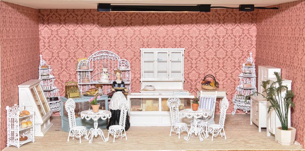 Furnished Room Box Bakery Dollhouse: Plywood room box has hinged front door, built in lighting in painted ceiling, paper covered walls and fabric covered floor, nice range of contents include four metal display racks loaded with cakes an