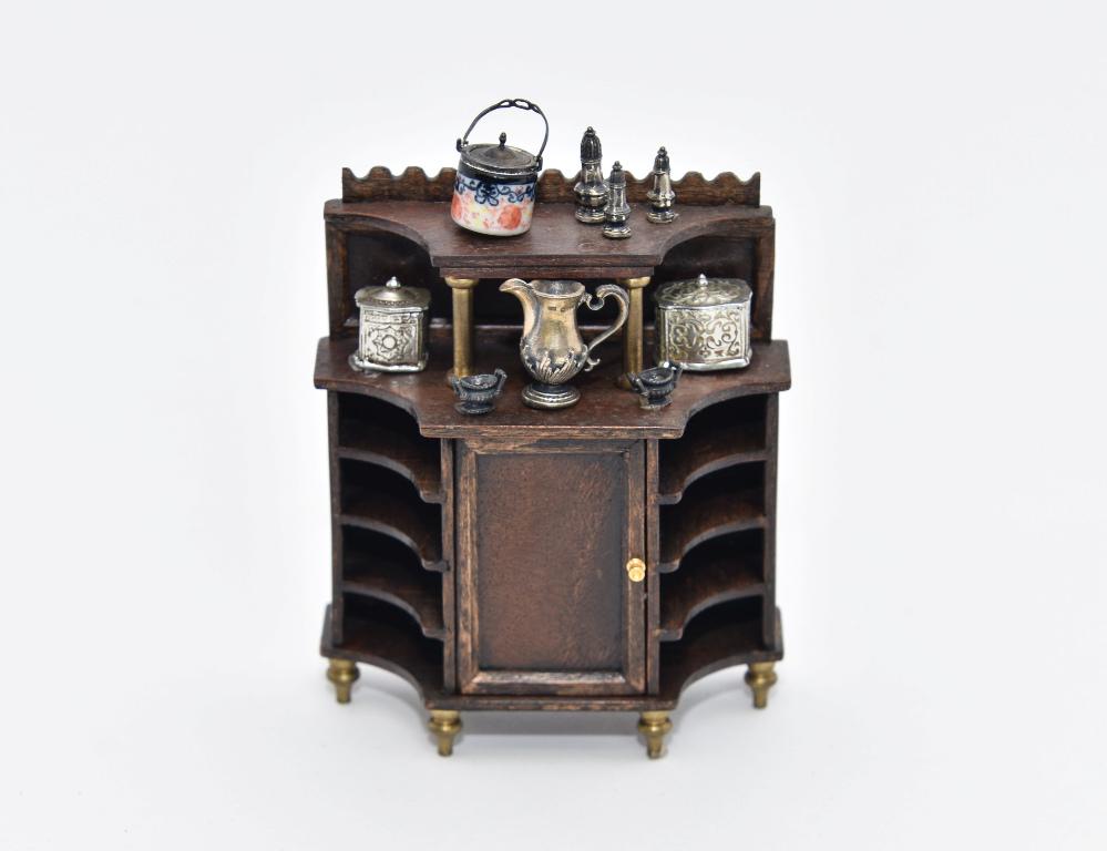 Trail-Hill Sideboard & Silver Accessories Miniatures: C.J. Trail Hill colorful dark mahogany sideboard with scalloped crest rail, single door flanked by curved shelves, brass knob and feet 3 1/8"W, 1.5"D, 3.75"H, comes with a Muriel Hopwood porcelain bis