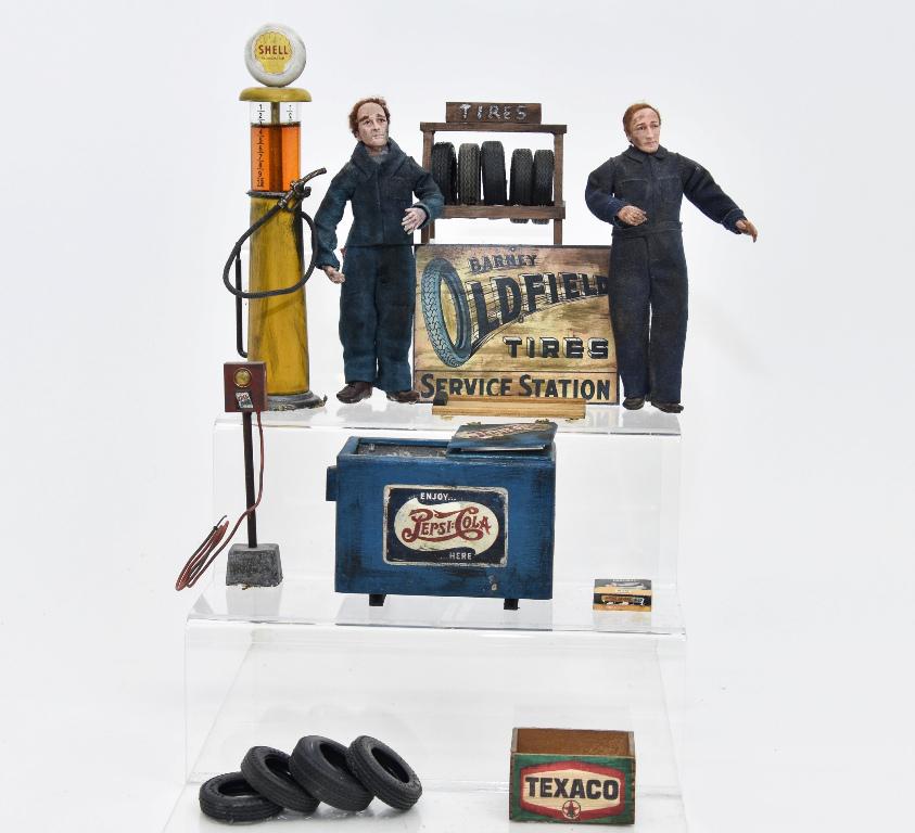 Two Marcia Backstrom Mechanic Dolls & Accessories: Two hand made artisan clay dollhouse dolls by Marcia Backstrom 6"H, tin and glass gas pump with distressed finish 7.5"H, wood Pepsi cooler with bottles on ice has a distressed finish 4.25"W, wood and 