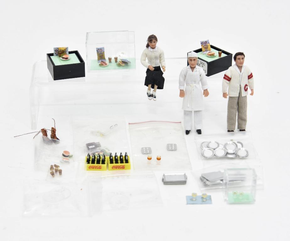 Dollhouse 1/2" Artisan Dolls & Food Miniatures: Three artisan 1/2" scale dolls by Kubish signed CMK, boy wearing his high school sports sweater 3"H, seated girl and a soda jerk 3"H, Sydnie Wagner pair of burgers, pair of hotdogs and bags of chips, 