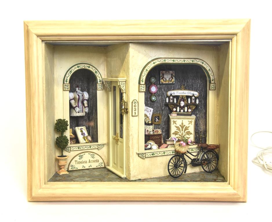 Artisan Shop Dollhouse Room Box: Wood room box painted with textured paint 14"W, 7.5"D, 11"H, interior has two shop windows filled with a variety of lady's' accessories, including a dress, shoes, perfumes, dishes, books etc., removab
