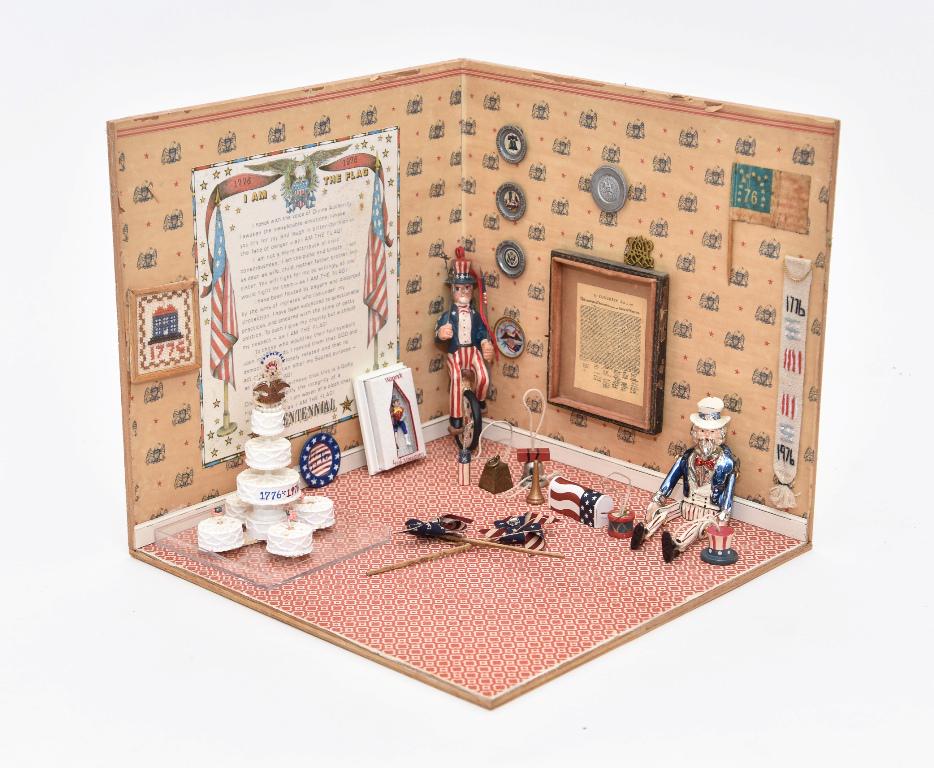 Bicentennial Celebration Diorama Room Box: Wood open room box diorama has paper covered walls and floor, framed Declaration Of Independence, pewter plates, needlepoint banner, Jone signed elaborate cake with eagle and fireworks topper 4.25"H, 