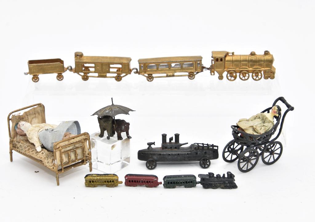 Small Antique Metal Miniature Toys & Furniture: Vintage soft metal bed with bisque doll 2.5"L, vintage stroller2"L with an antique carved Queen Ann wood doll 1.5"L with scattered shallow chips, antique cast metal elephant and bear walking under an 