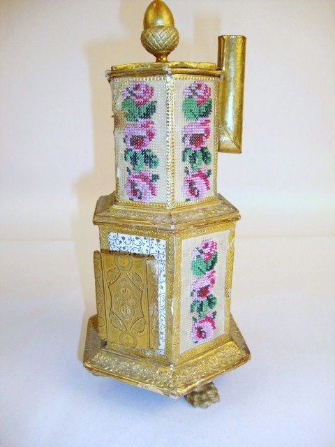Outstanding Viennese Candy Container Stove: A large candy container parlor stove 8.5" H featuring eight panels with glass beads embroidered on punched card, extensive Dresden paper trim, hairy paw feet, acorn finial and label on base identifyin