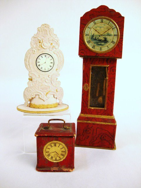 Candy Container Grandfather and Shelf Clocks: A tall case clock approx. 6" H with Delft scenic face, swinging pendulum and weights and a carriage clock with brass handle, both with red leatherette papering (some loss on carriage clock). Also a lo