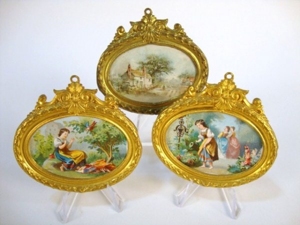 Ormolu Framed Pictures: Trio of oval framed prints with ormolu frames by Erhard & Sohne comprising one landscape and two of the same child playing in a garden (one loose from frame) 3.25" W.
