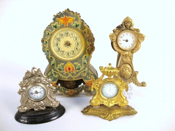 Victorian Gilded Mantle Clocks: An assortment of four antique clocks including a lithographed tin wind-up clock (missing hands) 4" H, a tin mantel clock, an ormolu mantel clock, and an unusual brass tabletop clock with elegant Beaux