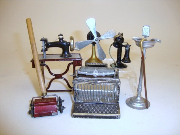 Assorted Vintage Metal Miniatures: A group of early 20th century metal accessories including a sturdy little sewing machine on stand with movable parts 3" H, a smoking stand, an electric fan, a carpet sweeper marked "IDEAL", a painted 