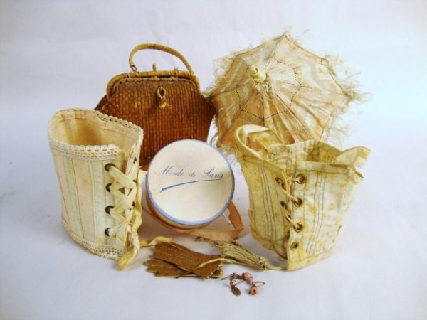 French Fashion Doll Accessories: Two early corsets, parasol with fringe and painted metal handle, one pair earrings, leather gloves, Mode de Paris Box, Wicker Basket, perfect for your doll! 3 1/2" H