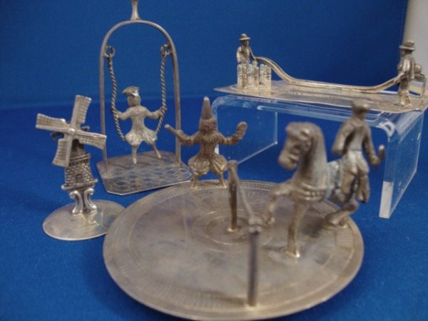 Three Dutch Silver Toys and Windmill: A man on a swing with Amsterdam mark & date letter C, unclear maker's mark, a circus scene with jumping horse & rider with 3 decorative marks, two men bowling marked Holland sterling, with windmill 3"