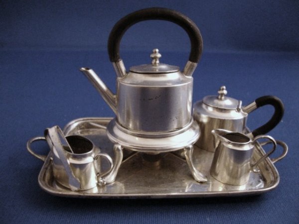 Meyers Tea Set on Tray: Meyers 8-pc tea set on tray with an oval bodied kettle on stand, teapot with similarly formed tapered body, sugar and creamer, the stand with four pad feet and burner, kettle and pot with dark loop wo