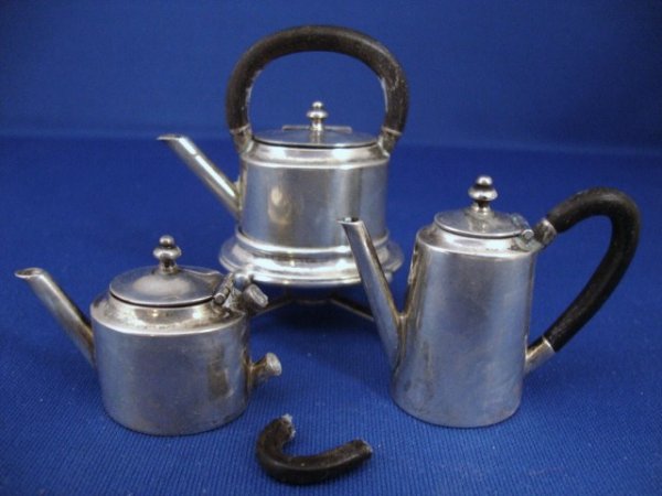 Emma Haig Kettle, Tea and Coffee Pot: Kettle on stand, teapot and coffee pot of oval body form variously tapered, with hinged oval lids and turned finial, straight spouts and loop-formed handles. The kettle stand on four bracket feet with